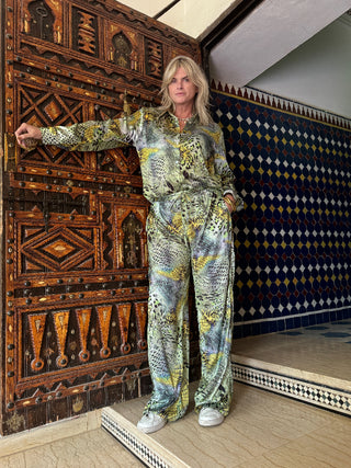 Person wearing a patterned outfit standing in a room with ornate wooden paneling and tiled walls.