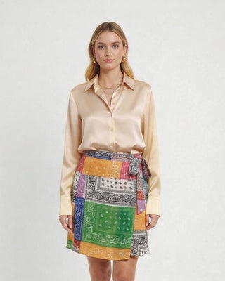 Woman wearing a Champaign blouse  with French Cuffs on the bandana patterned wrap skirt on a white background