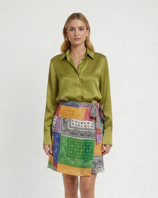 Woman wearing a Olive blouse with French Cuffs on the bandana patterned wrap skirt on a white background