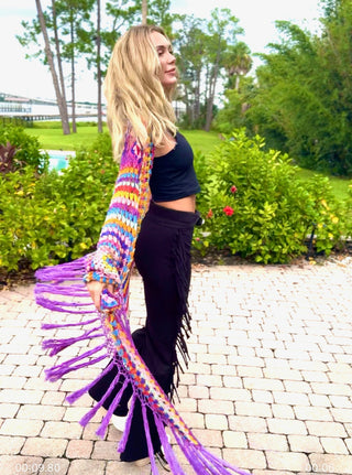 Side view of the crochet duster swinging out, purple fringe flying, with black fringe pants