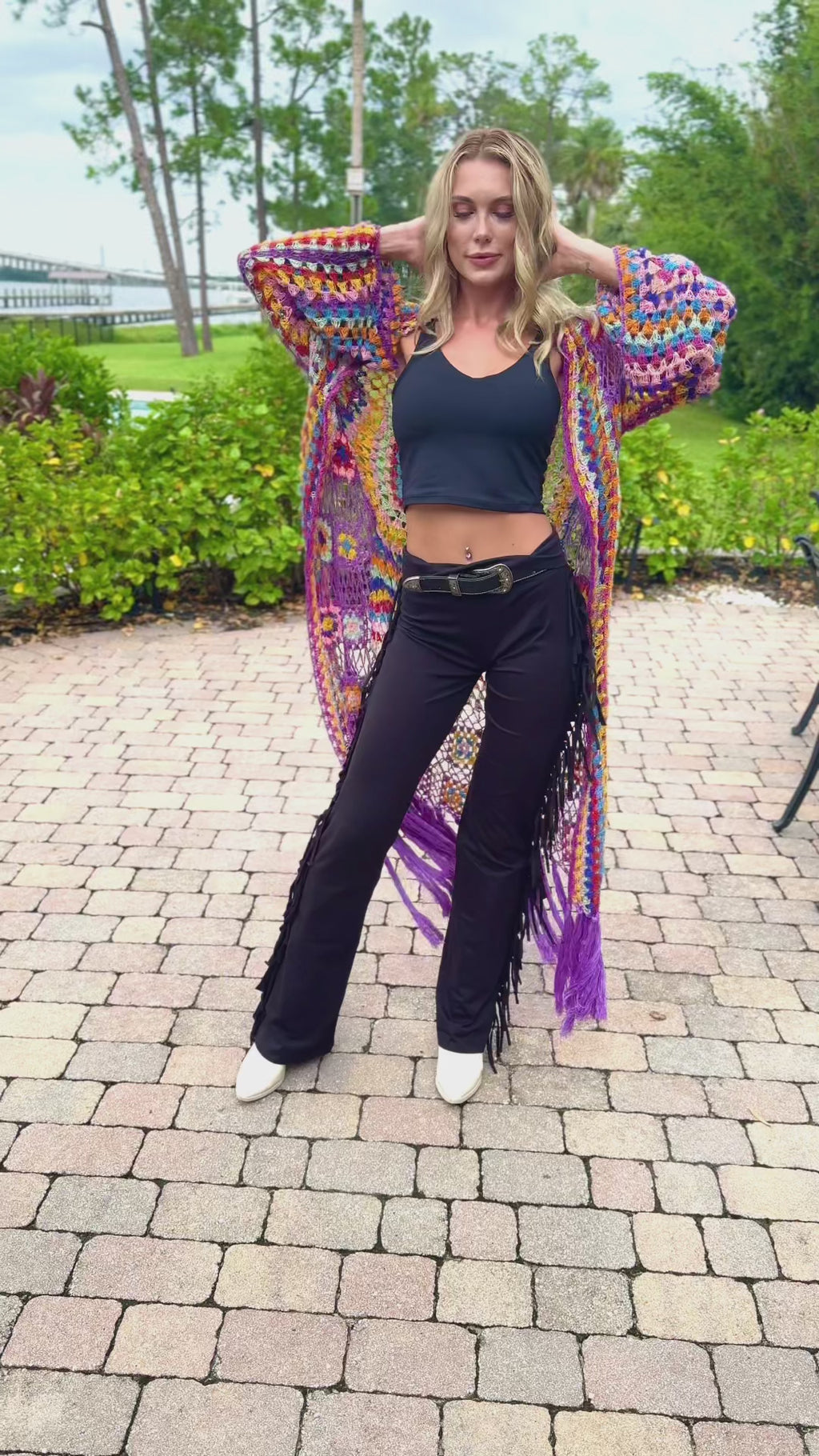 Tall model turning in the rainbow crochet duster so the purple fringe swings